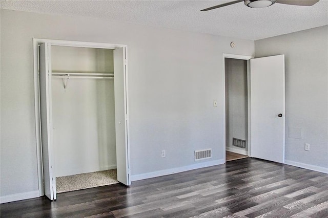 unfurnished bedroom featuring a textured ceiling, ceiling fan, visible vents, a closet, and wood finished floors