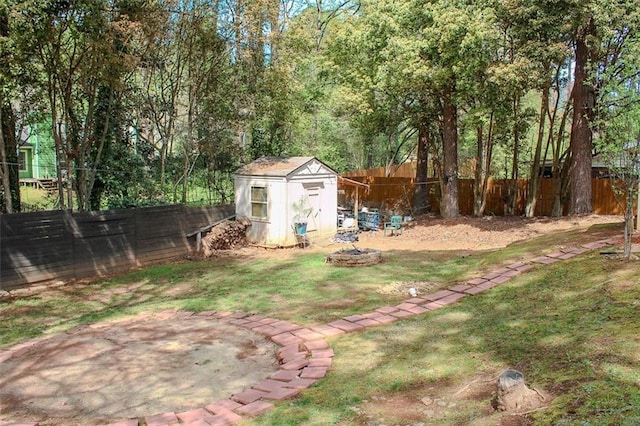 view of yard featuring an outbuilding, a fire pit, a fenced backyard, and a storage unit
