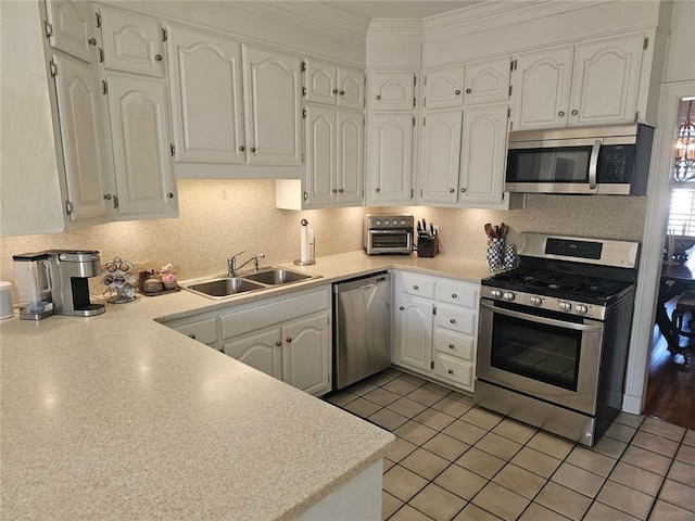 kitchen featuring light countertops, appliances with stainless steel finishes, a sink, and white cabinets