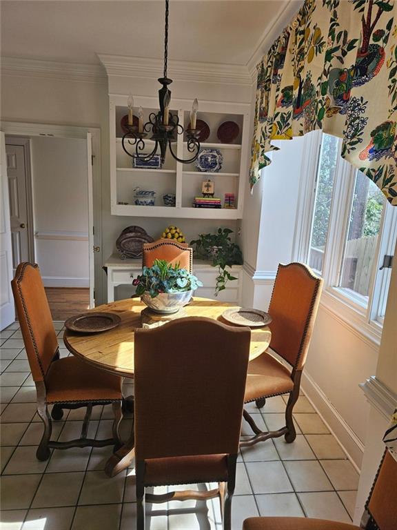 dining room with light tile patterned flooring, crown molding, baseboards, built in features, and an inviting chandelier