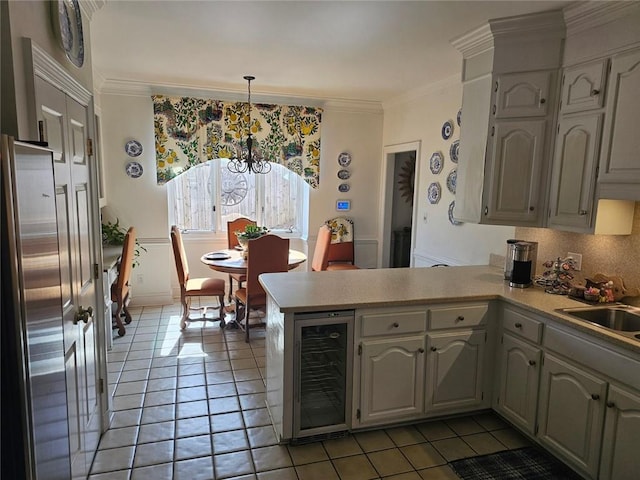 kitchen featuring wine cooler, a peninsula, light countertops, pendant lighting, and a sink