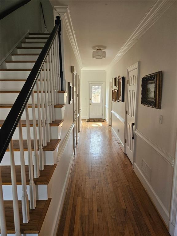 hall featuring baseboards, visible vents, dark wood-type flooring, stairs, and crown molding