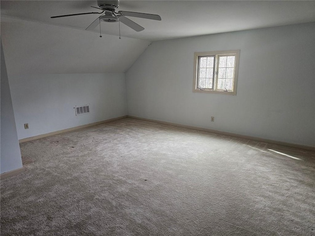 additional living space with visible vents, baseboards, ceiling fan, carpet, and vaulted ceiling