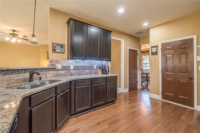 2235 Well Springs Dr, Buford, GA 30519 - kitchen with a sink, light wood-type flooring, tasteful backsplash, light stone counters, and a ceiling fan