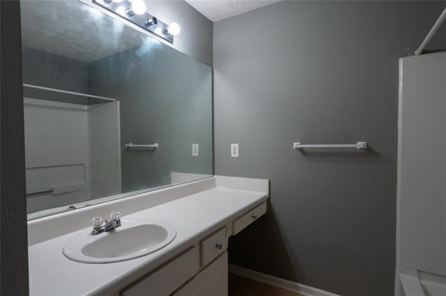 full bath featuring a textured ceiling, walk in shower, and vanity