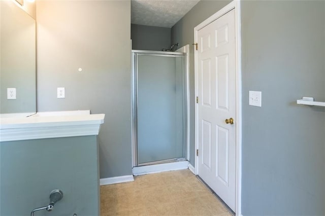 bathroom with a shower stall, baseboards, and a textured ceiling