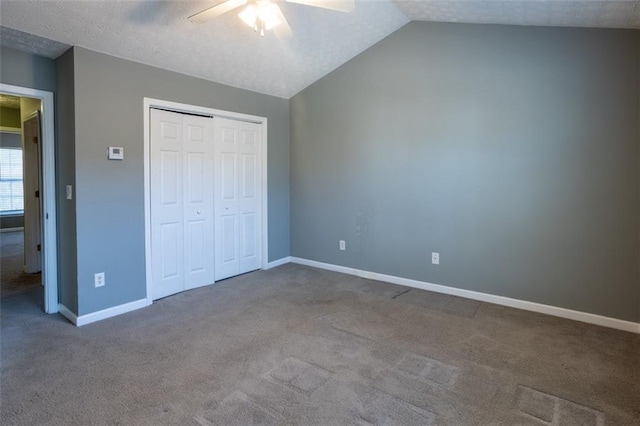 unfurnished bedroom featuring carpet, lofted ceiling, a closet, a ceiling fan, and baseboards