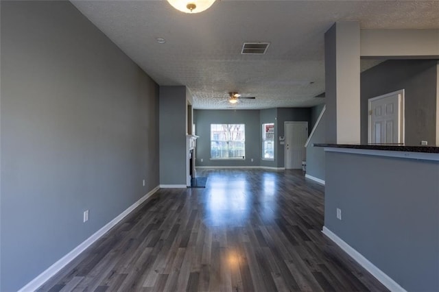 interior space with dark wood-style floors, ceiling fan, visible vents, and baseboards