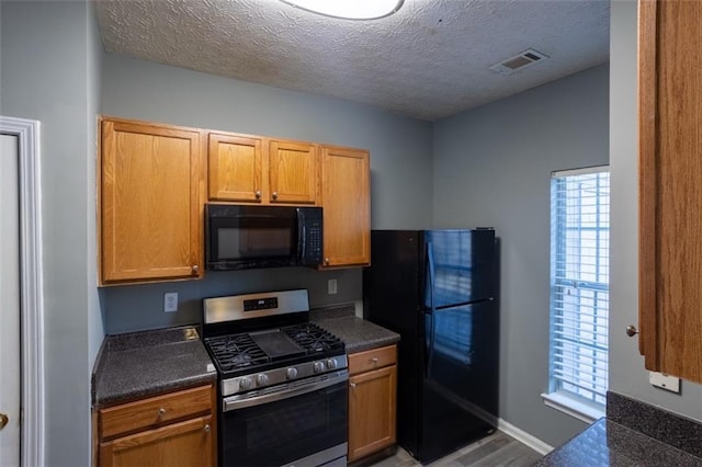 kitchen featuring dark countertops, visible vents, black appliances, a textured ceiling, and baseboards