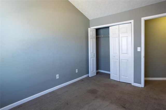 unfurnished bedroom with baseboards, carpet, vaulted ceiling, a textured ceiling, and a closet