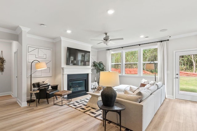 living area with baseboards, a fireplace with flush hearth, light wood-style flooring, and crown molding