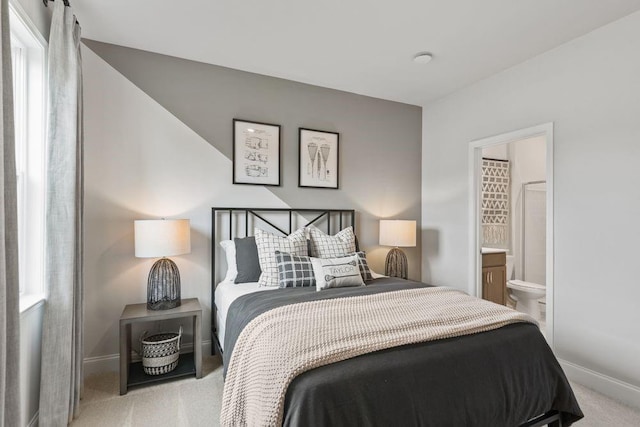 bedroom with carpet floors, connected bathroom, and baseboards