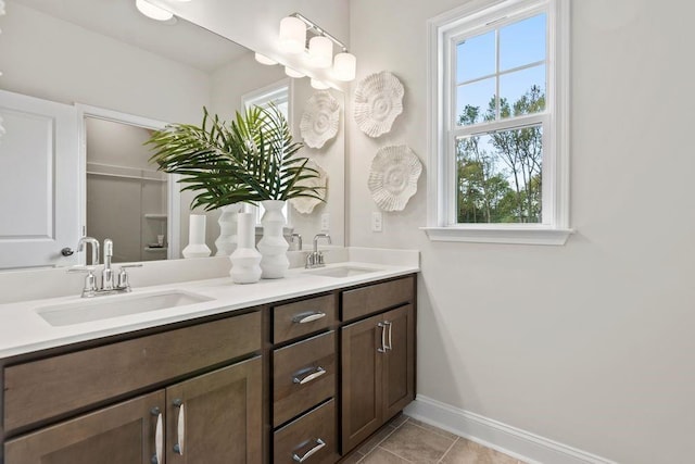 bathroom with double vanity, tile patterned flooring, baseboards, and a sink