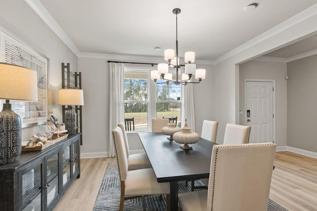 dining room with light wood-style floors, a chandelier, crown molding, and baseboards