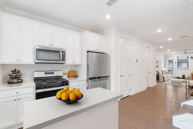 kitchen featuring white cabinets, backsplash, ceiling fan, stainless steel appliances, and light wood-type flooring