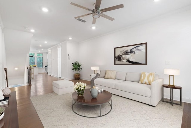 living room with ceiling fan, ornamental molding, and light wood-type flooring