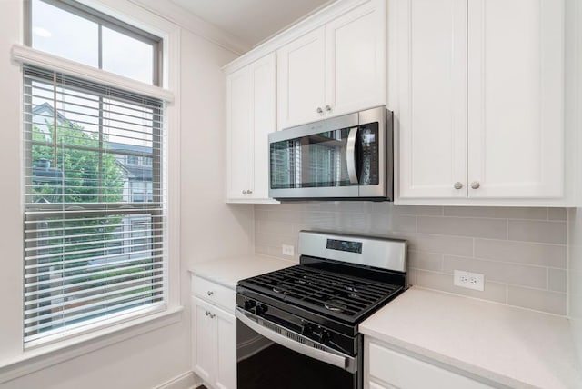 kitchen with white cabinetry, decorative backsplash, crown molding, and gas stove