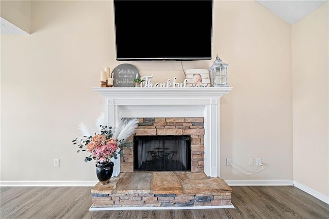 room details featuring a fireplace, wood finished floors, and baseboards