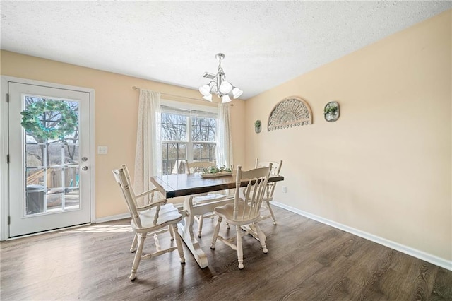 dining room featuring a notable chandelier, a textured ceiling, baseboards, and wood finished floors