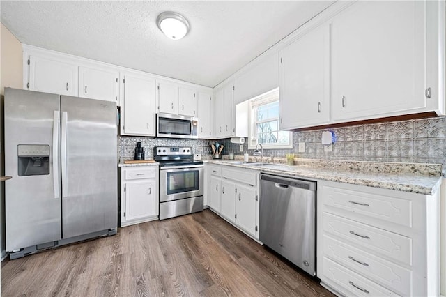 kitchen featuring appliances with stainless steel finishes, white cabinetry, a sink, and tasteful backsplash