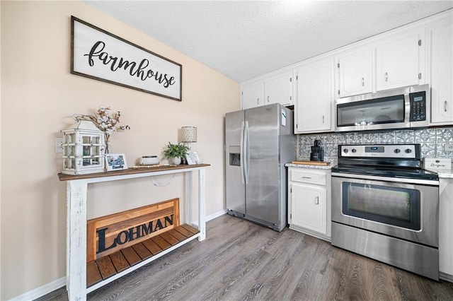 kitchen with stainless steel appliances, wood finished floors, white cabinets, and tasteful backsplash