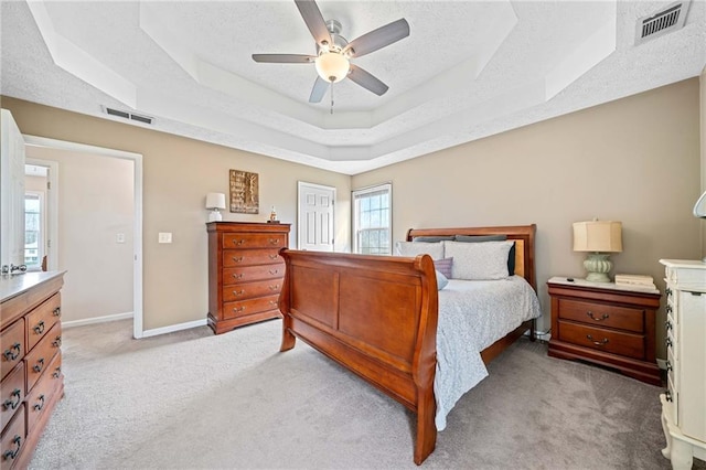 bedroom featuring a textured ceiling, a tray ceiling, and visible vents