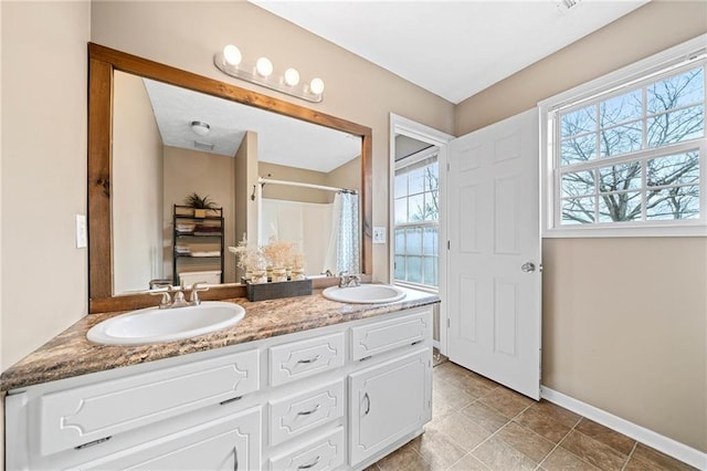 bathroom with curtained shower, a sink, baseboards, and double vanity