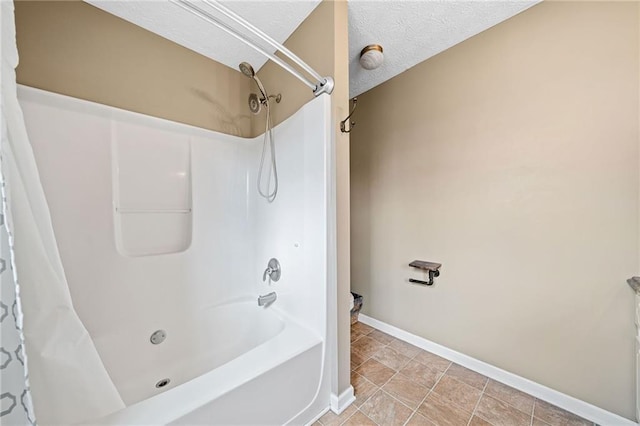 full bath with shower / tub combo, baseboards, and a textured ceiling