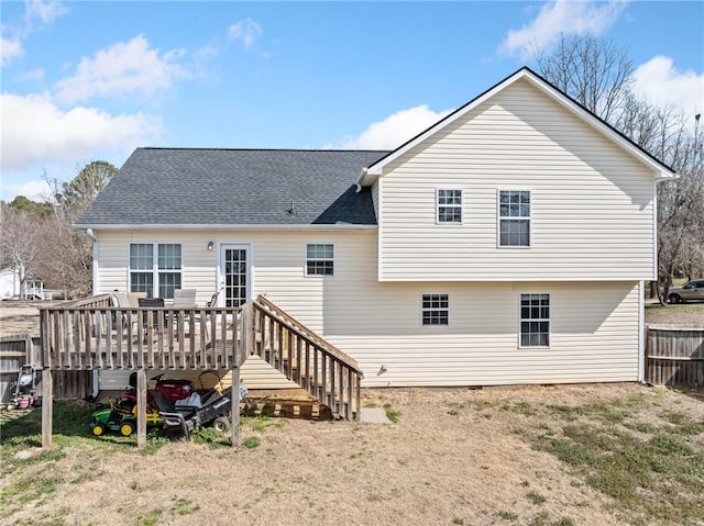 rear view of property featuring a shingled roof, fence, and a wooden deck