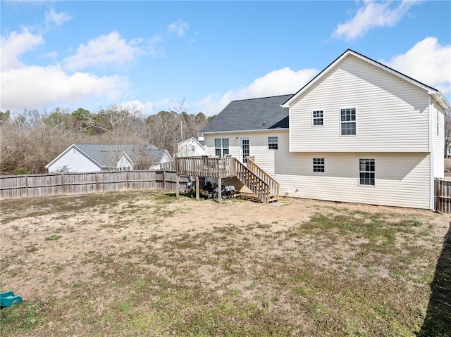 back of property with a fenced backyard, stairway, a deck, and a lawn