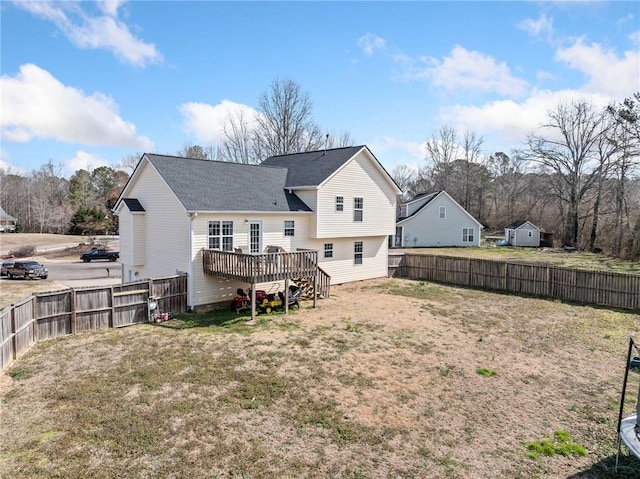 back of house with a fenced backyard, a yard, and a deck