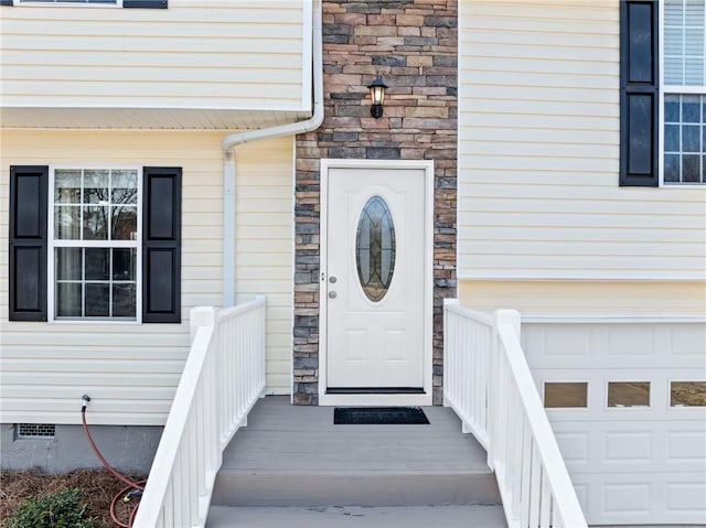 doorway to property with stone siding, an attached garage, and crawl space