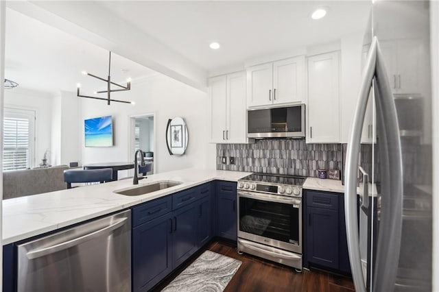 kitchen featuring white cabinets, a peninsula, a sink, light stone counters, and appliances with stainless steel finishes