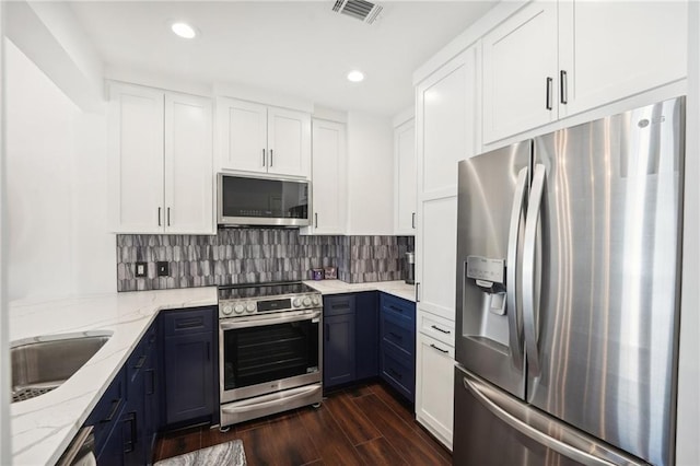 kitchen featuring light stone counters, stainless steel appliances, visible vents, a sink, and dark wood-type flooring