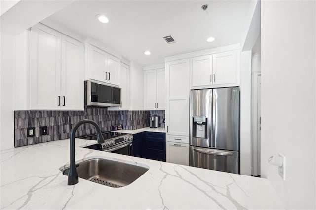 kitchen with a sink, tasteful backsplash, visible vents, white cabinetry, and appliances with stainless steel finishes