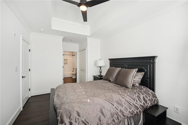 bedroom featuring crown molding, ensuite bathroom, dark wood-style floors, and a raised ceiling