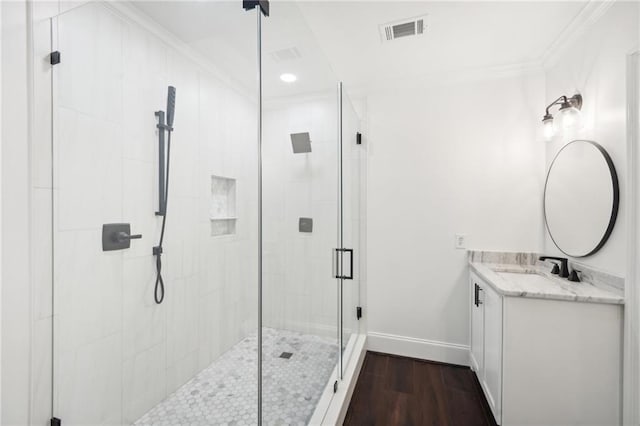 bathroom featuring a stall shower, visible vents, baseboards, wood finished floors, and vanity