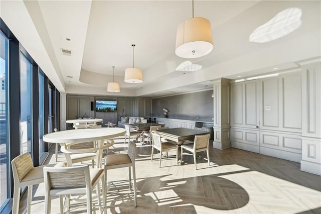 dining room featuring a raised ceiling, a decorative wall, wainscoting, and visible vents