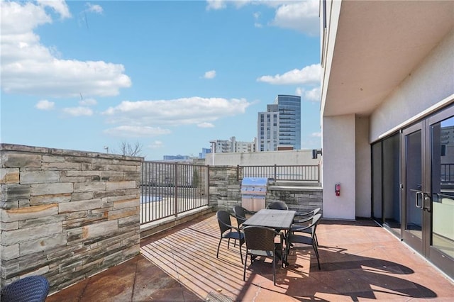 balcony with a patio area, a city view, outdoor dining area, and a grill