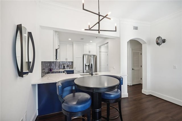kitchen featuring white cabinets, stainless steel fridge with ice dispenser, visible vents, a peninsula, and tasteful backsplash