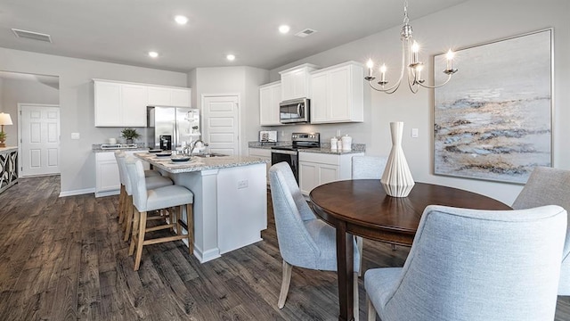 kitchen featuring a center island with sink, visible vents, dark wood finished floors, appliances with stainless steel finishes, and a sink