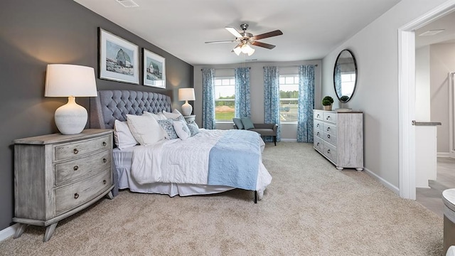 bedroom with light carpet, ceiling fan, visible vents, and baseboards