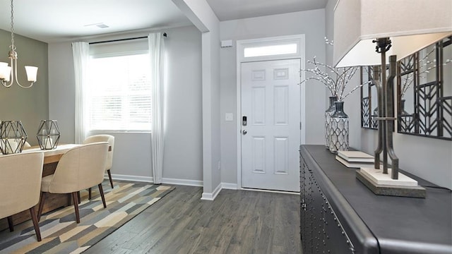 entrance foyer with a chandelier, dark wood-style flooring, and baseboards