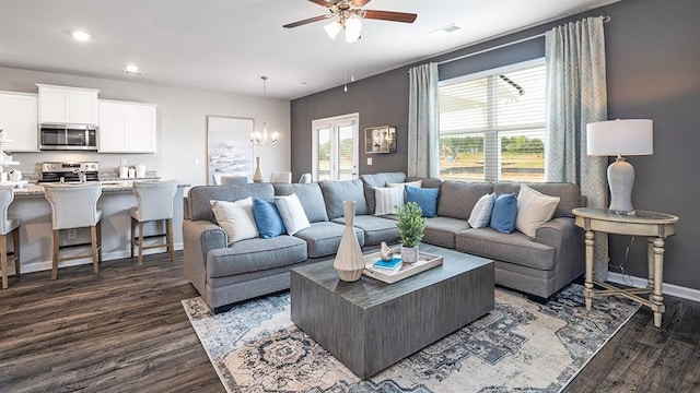 living room with dark wood-style floors, recessed lighting, baseboards, and ceiling fan with notable chandelier