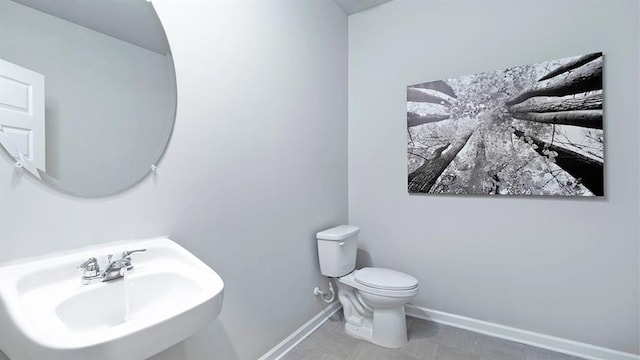 half bathroom featuring a sink, toilet, and baseboards