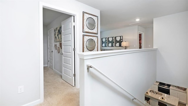 corridor featuring baseboards and light colored carpet