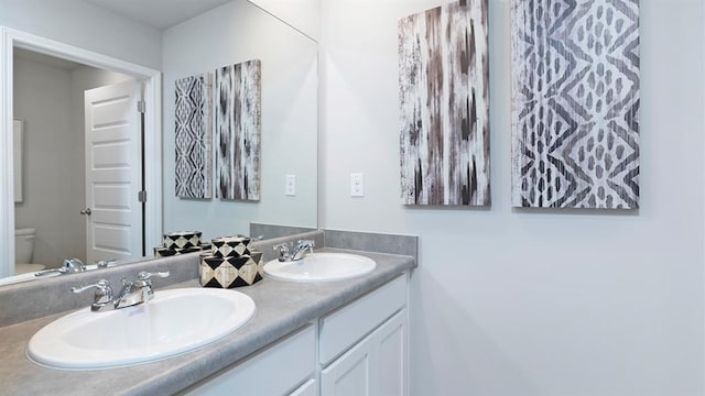 bathroom with double vanity, a sink, and toilet