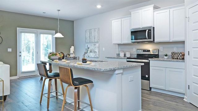 kitchen featuring appliances with stainless steel finishes, wood finished floors, a breakfast bar, and white cabinetry