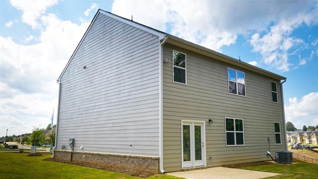 rear view of house with brick siding, cooling unit, a patio, and a yard