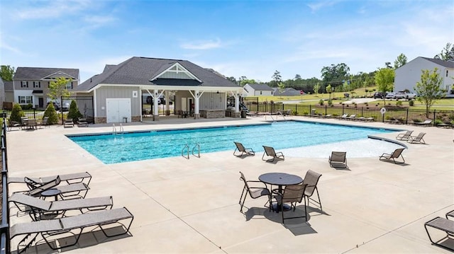 community pool with a patio area and fence